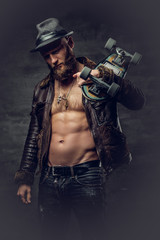 Fototapeta na wymiar Bearded male dressed in leather jackett holds skateboard.