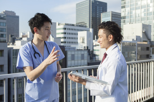 Two young doctors are talking on the roof of the hospital