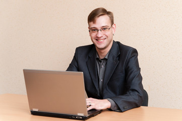 Man in glasses works on laptop