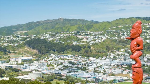 Wellington NZ Red Maori Wooden Carved Artwork with City Mountains Landscape Background with Residential Neighborhoods