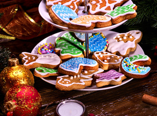 Christmas Cookie of Gingerbread. Sweet course of confection on dessert stand. Two level of pastry. Xmas ball foreground. Candle on wooden table. Colourful biscuit on plate. Holiday food in restaraunt.