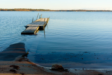 Empty floating swimming pier in calm and windless sea. Water level is high and the bridge is surrounded by seawater.