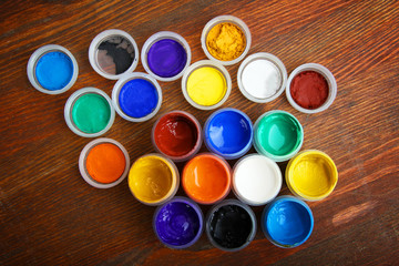 A variety of multi-colored gouache paint on a wooden background.
