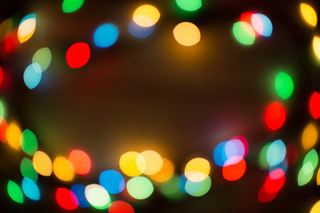 Bokeh lights. Color light on black background. Christmas or other holiday decorations, garland illumination bokeh. Abstract circular light bokeh New Year Festive background, decorated tree bokeh.