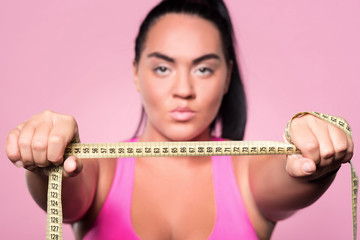 Close up of plumb woman showing body measuring tape