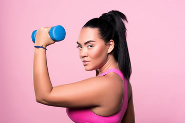 Side view of chubby woman holding dumbbell