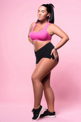 Fototapeta na wymiar Pleasant confident plump woman posing on pink background