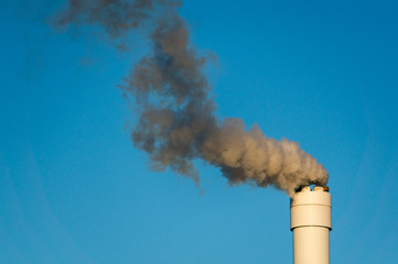 polluted smoke against a clear blue sky from the tall chimney