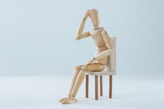 Tired wooden figurine with hand on forehead
