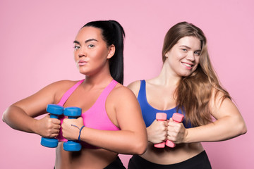 Two woman posing on pink background