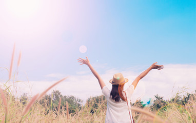 woman traveler with camera holding hat and breathing at field of grasses and forest, wanderlust...