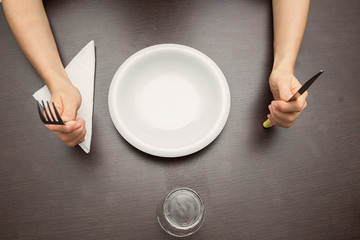forchetta, coltello e piatto con mani in attesa di mangiare