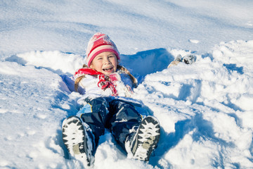 Fototapeta na wymiar Happy little girl playing on winter snow day.