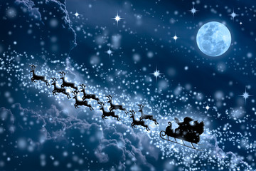 Christmas blue background. Silhouette of Santa Claus flying on a sleigh pulled by reindeer. 