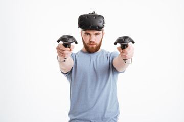 Concentrated man wearing virtual reality device standing over white background