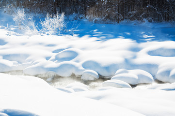 Forest river after snowfall on a cold sunny day