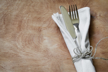 Fork and Knife Tied on White Napkin on Wooden Table. Table Setting,