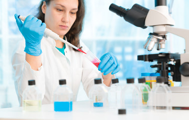 Woman technician with multipipette in genetic laboratory PCR research. Student girl use pipette. Young female scientist loads samples for DNA amplification by PCR