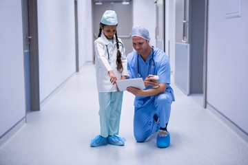 Smiling doctor and girl using digital tablet in corridor