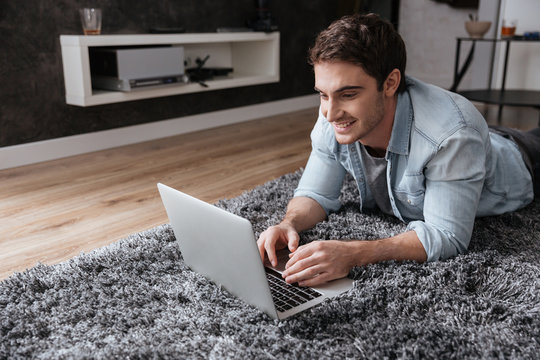 Man using laptop while lying on carpet at home