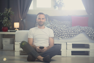 Fototapeta premium Portrait of a male using his smartphone in his bedroom