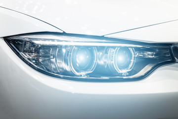 Closeup headlights of modern car during turn on light in night.