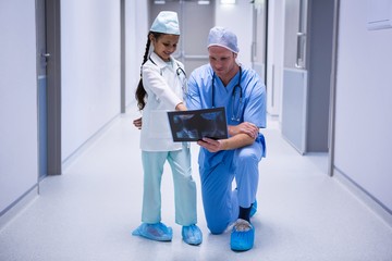 Smiling girl and doctor looking at x-ray in corridor