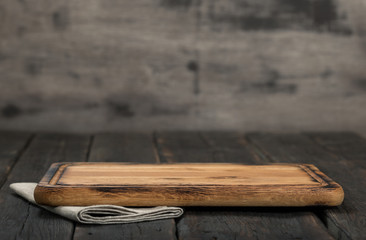 Chopping board on dark wooden background close up