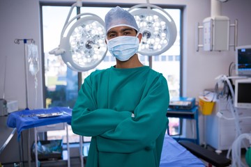 Portrait of surgeon standing with arms crossed in operation room