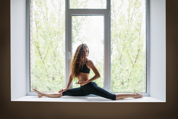 Obraz na płótnie Canvas Beautiful woman doing yoga asana on window sill