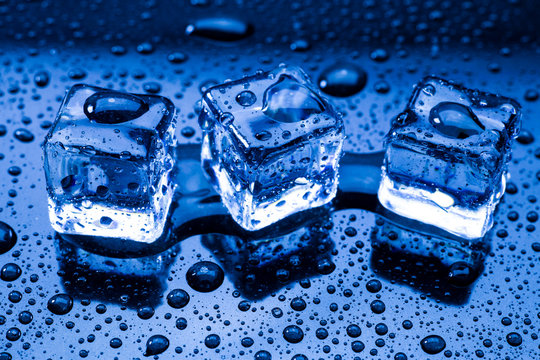 Wet ice cubes and water drop on blue background.