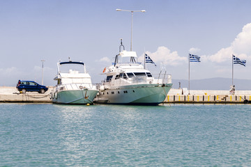 two boats at the pier on the background of the Greek flag, the Ionian Sea