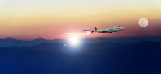 Fototapeta na wymiar White passenger plane flying in the blue sky above the mountains