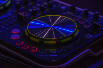 Close-up of DJ mixer console with backlighted buttons and slider