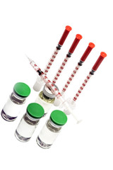 Four medical insulin syringes, one syringe without needle cap lying on medical bottle, three more ampules with insulin hormone. Isolated on white background. Top angle view.
