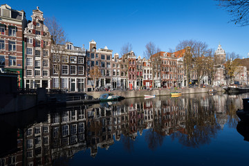 Fototapeta premium Przebudowane magazyny Amsterdamu odbijają się w jednym z jego kanałów