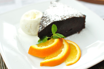 A piece of with ball of vanilla ice cream, three orange slices and mint spring