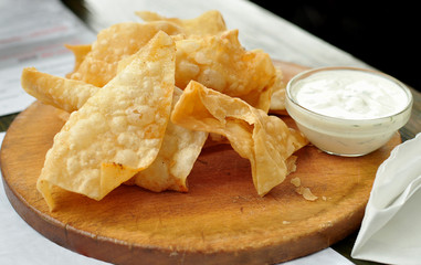 Potato chips on a wooden cutting board on a table. Concept of unhealthy food.