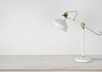 White lamp on wooden desk in room with copy space