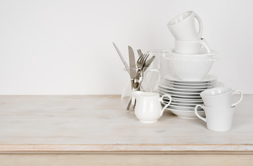 White dishware and cutlery on wooden table with copy space