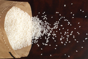 White rice in paper bag on wood background