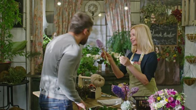 Professional florist telling to male customer about flowers and showing him hyacinths at flower studio