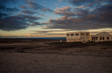 tramonta il sole su una struttura abbandonata tra deserto e mare
