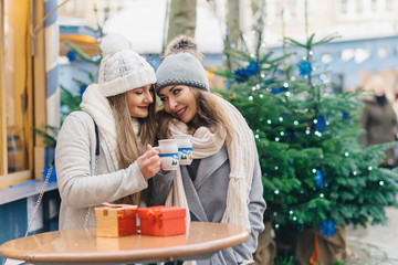 two female best friends drinking mulled wine on christmas deco o