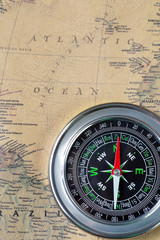 The Black compass on old vintage map, atlantic ocean, macro background
