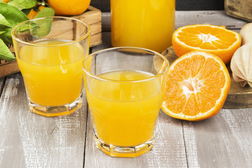 Tangerine juice in glass and fresh fruit on a wooden background