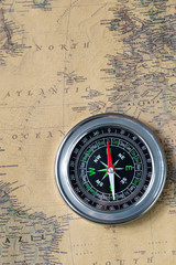 the Black compass on old vintage map, north atlantic ocean, macro background