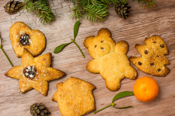 special christmas cookies among mistletoe, mandarin and christmas tree branches on a wooden table