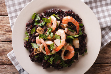 Black rice with shrimp, calamari, mussels and scallops closeup. Horizontal top view