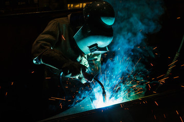 Fototapeta na wymiar Welder of Metal Welding with sparks and smoke in manufacturing